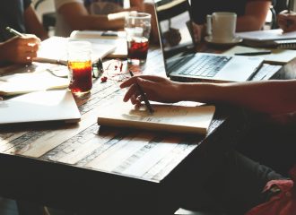 People working at table-laptops-notebooks-pens-glasses of coke-cup of coffee
