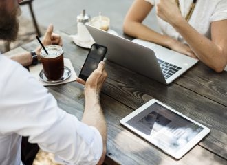 2 people sitting across table-laptop-tablet-smartphone-drink to illustrate Shareholder Protection