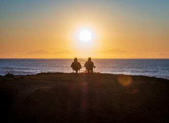 2 pensioners sitting facing the sea in the sunset