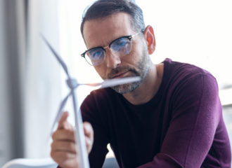 man wearing glasses looking at model wind turbine