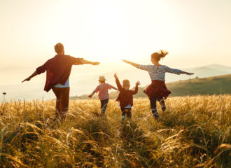 Family running with their arms extended in a field