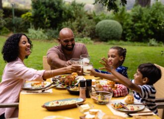 A family eating a meal outdoors and making a toast